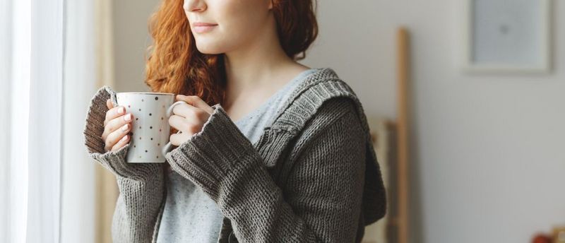 Eine junge Frau nimmt eine Auszeit und trinkt eine Tasse Tee