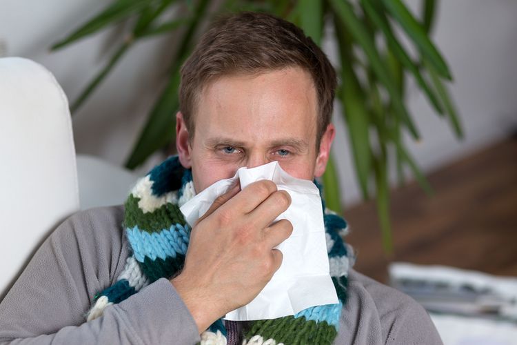 Mann leidet an einer starken Männergrippe und putzt sich die Nase