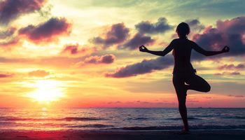 Frau macht Yoga am Strand, um Ihre Selbstkontrolle zu stärken.