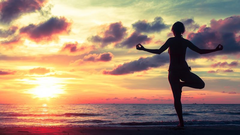 Frau macht Yoga am Strand, um Ihre Selbstkontrolle zu stärken.